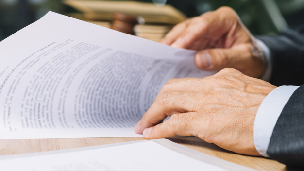 male-lawyer-s-hand-holding-document-desk-courtroom_23-2147898384