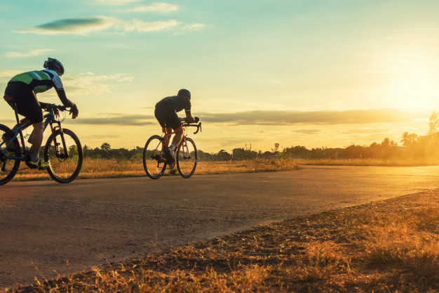 silhouette-group-men-riding-bicycle-sunset_36326-363